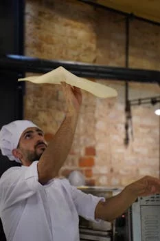 pizza chef tossing dough in kitchen